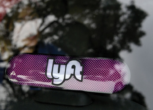 The lyft ride-sharing company's in-car signage and a view of trees in the background.