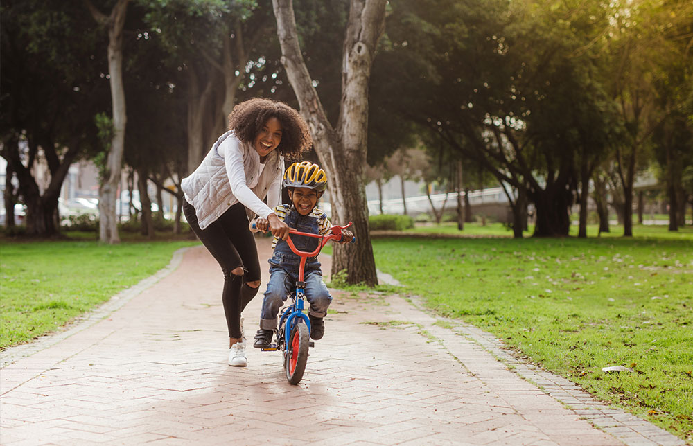 Mom teaching the son how to ride a bike.